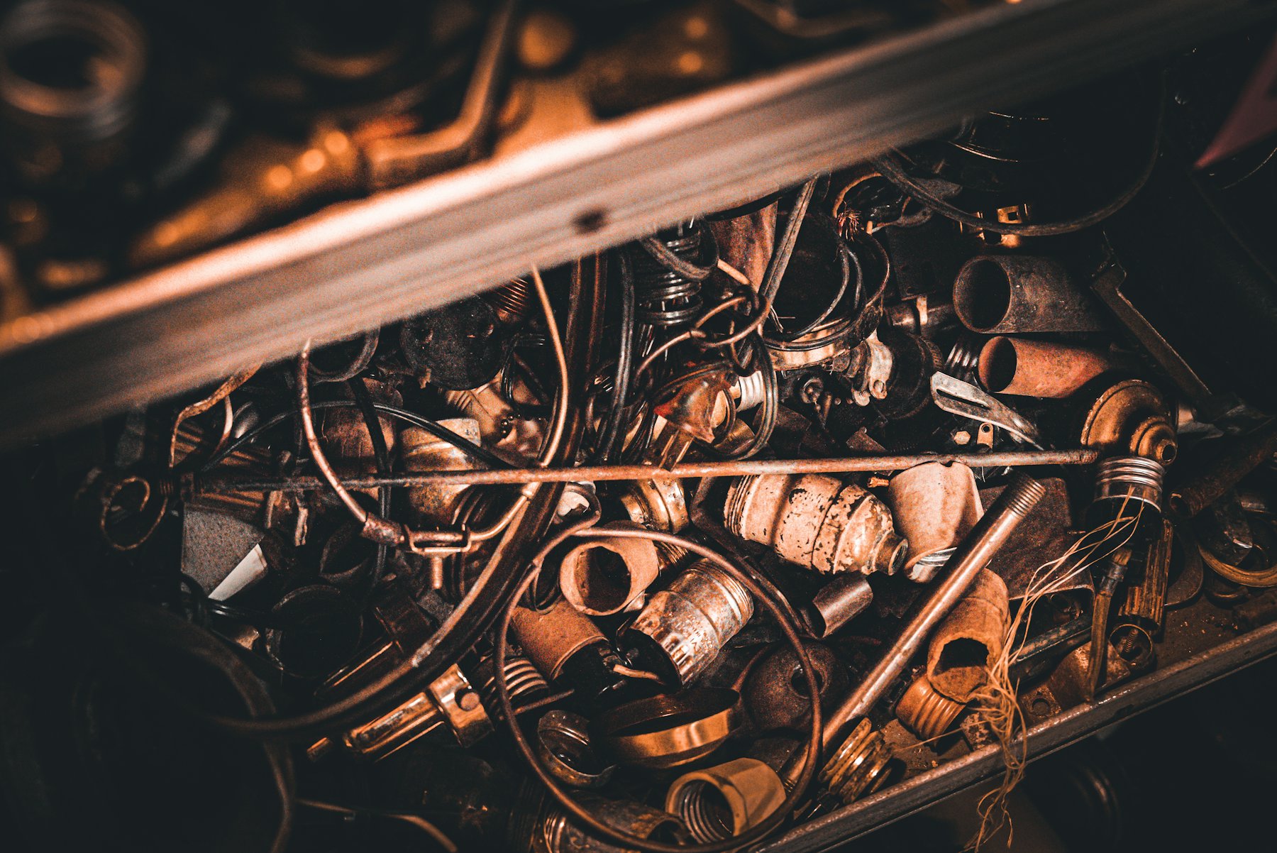 Assorted brass and copper scrap parts in a metal tray